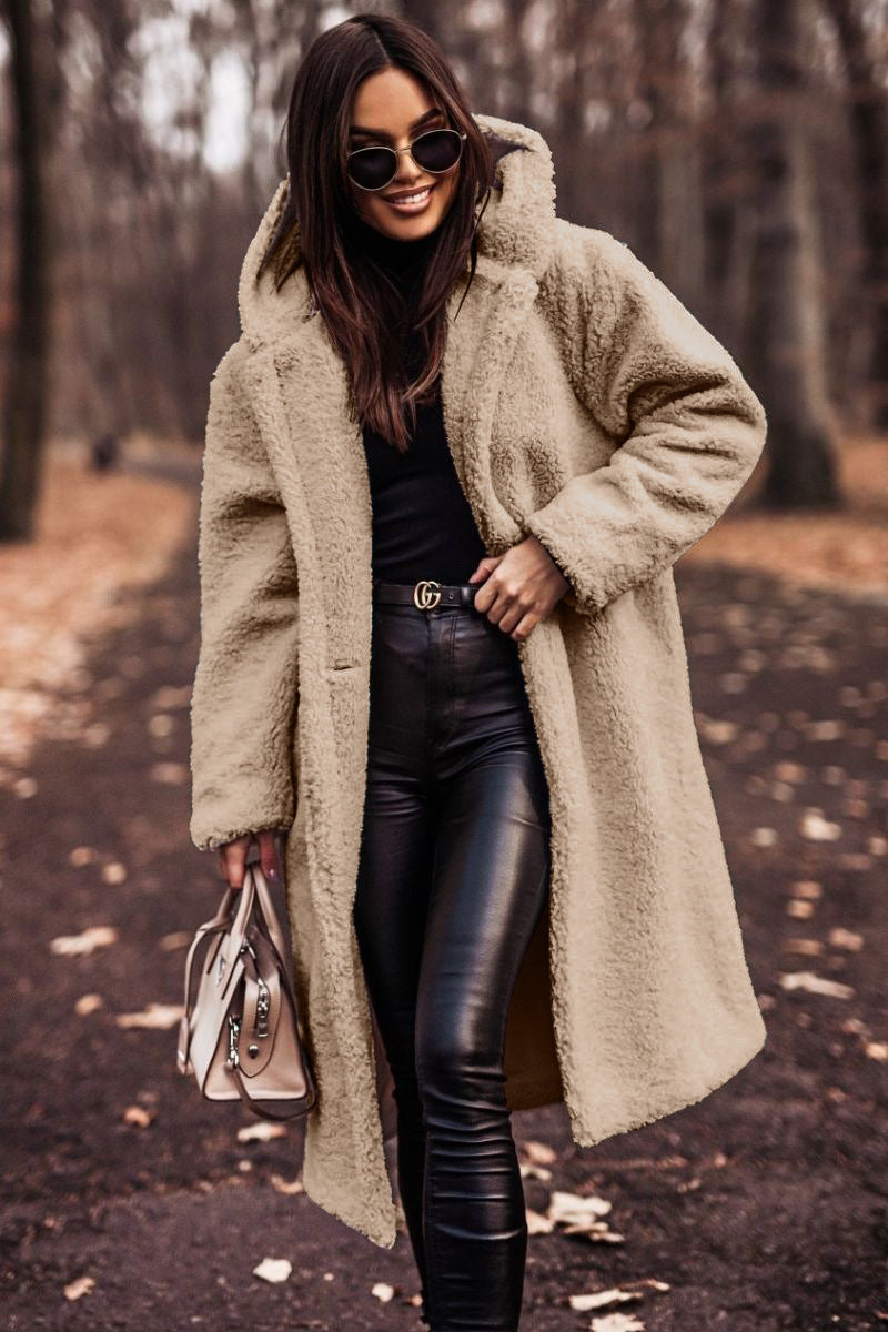 Donna con cappotto teddy beige, occhiali da sole e pantaloni in pelle nera, cammina in un parco autunnale. Moda autunno inverno, stile elegante.