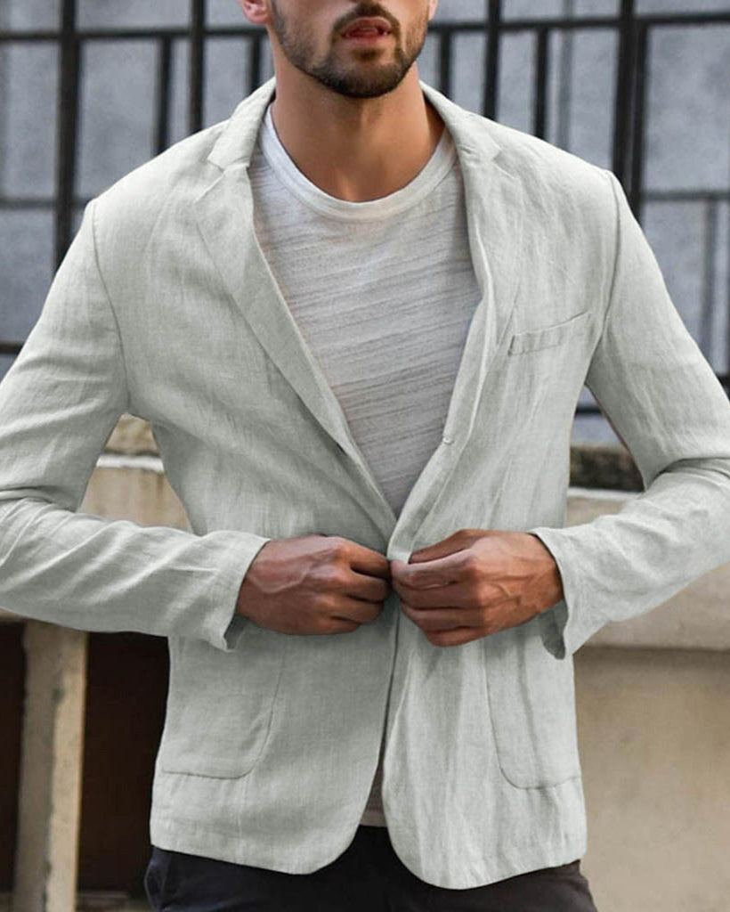 Uomo in giacca di lino grigia, t-shirt bianca, sfondo urbano. Moda maschile elegante, abbigliamento casual, stile contemporaneo.