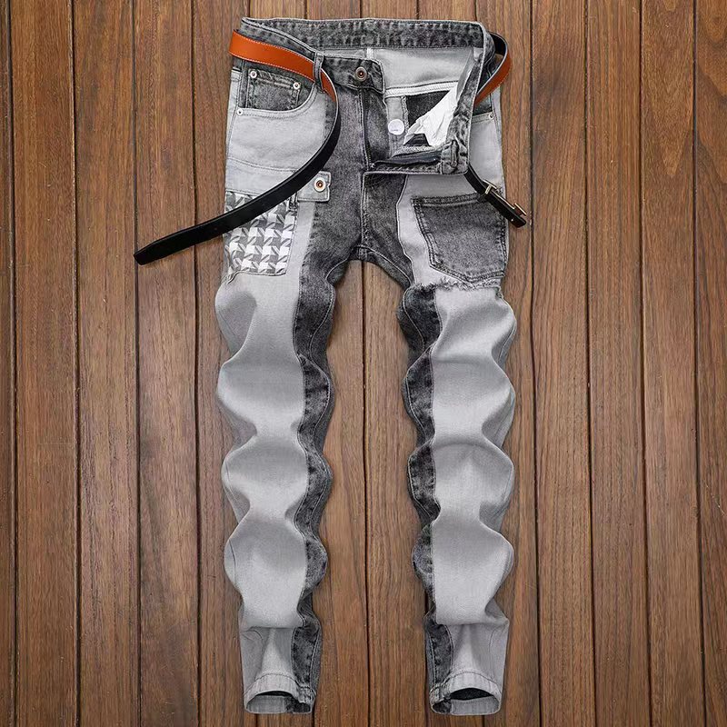 Jeans slim fit da uomo in denim grigio con dettagli a contrasto, cintura in pelle marrone, su pavimento in legno. Moda casual maschile.