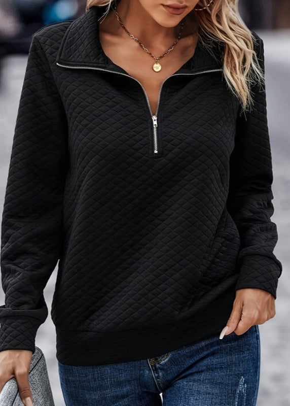 Donna con maglione nero trapuntato con zip, collana dorata, jeans blu. Moda autunno, abbigliamento casual elegante, stile urbano.