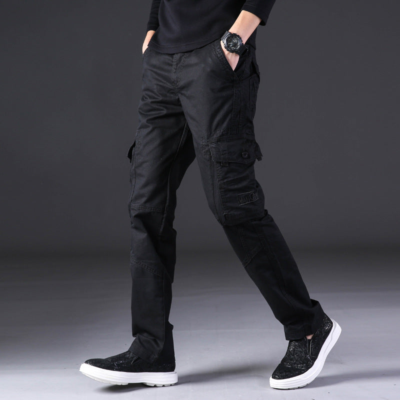Pantaloni cargo neri da uomo, stile casual, con tasche multiple, abbinati a scarpe sportive nere e maglia scura. Moda maschile contemporanea.