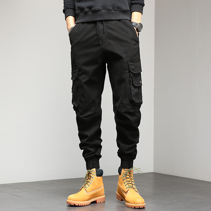 Pantaloni cargo neri da uomo con tasche multiple, abbinati a stivali gialli in pelle. Stile casual e moderno, perfetto per l'abbigliamento urbano.