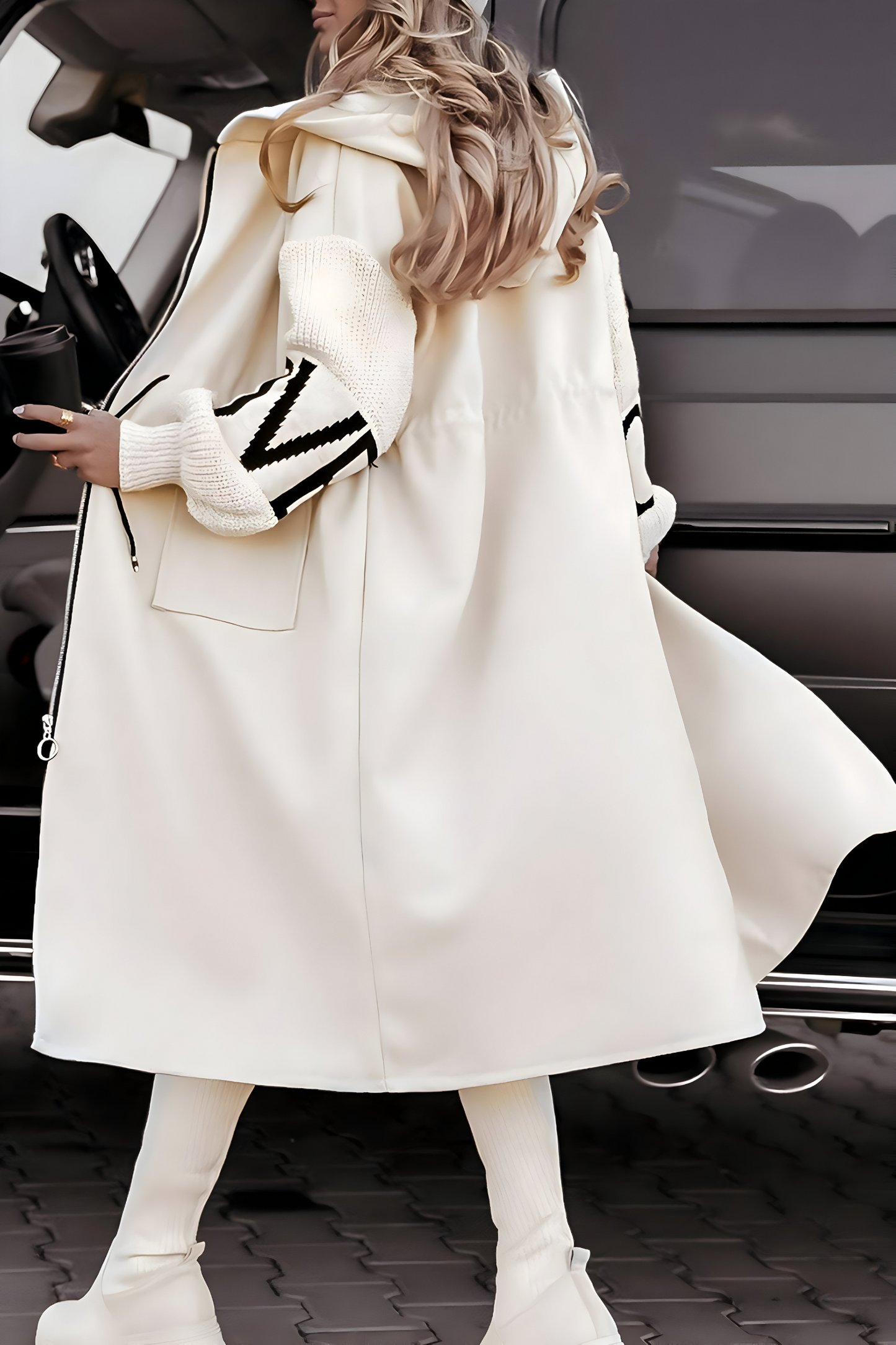 Donna con cappotto bianco elegante, stivali alti e capelli lunghi, accanto a un SUV grigio. Moda invernale, stile urbano, tendenze 2023.