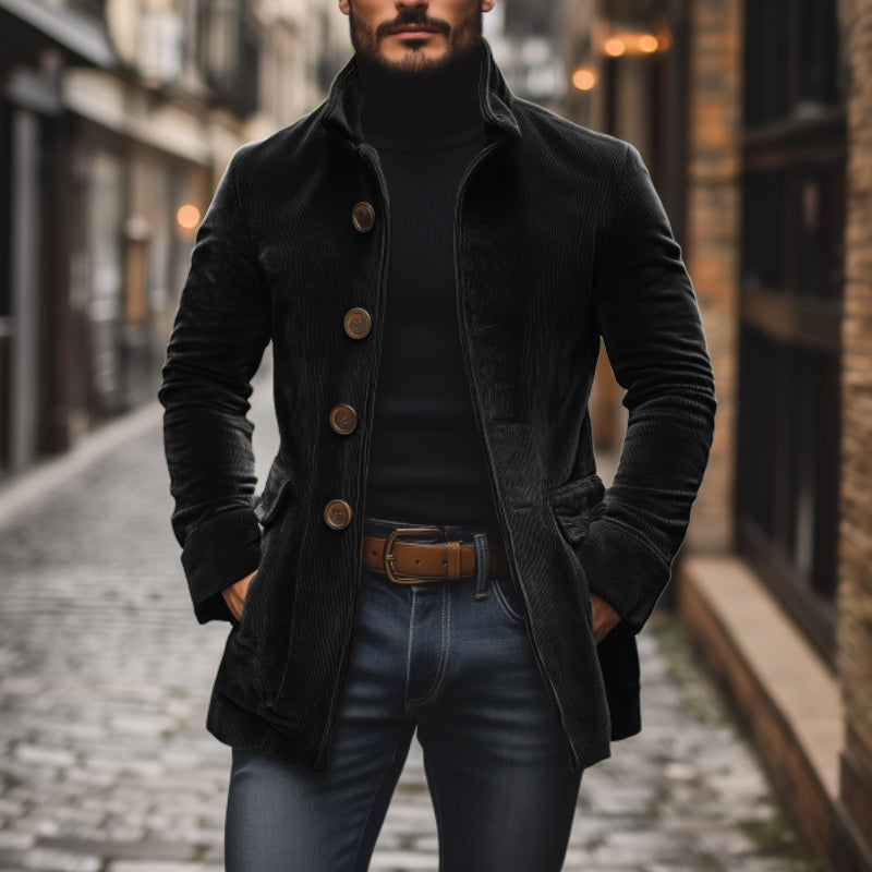 Uomo con cappotto nero elegante, dolcevita e jeans in una strada acciottolata. Moda maschile autunnale, stile urbano sofisticato.