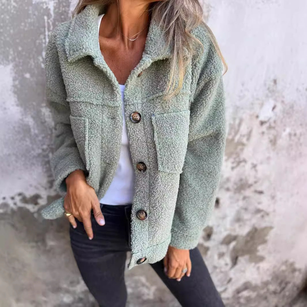 Giacca in pile verde salvia con bottoni, indossata da una donna su sfondo grigio. Moda autunnale, abbigliamento casual, stile confortevole.