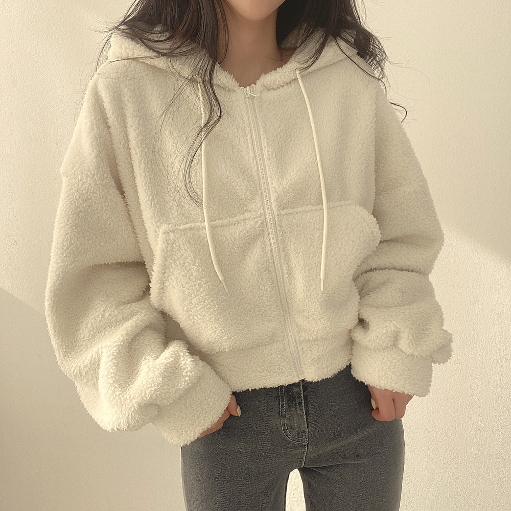 Donna con giacca in pile bianco, cappuccio e zip, indossa jeans grigi. Moda casual autunnale, abbigliamento caldo e confortevole.