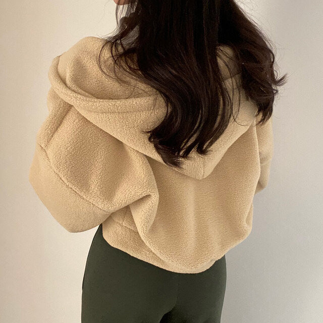 Donna con giacca in pile beige e cappuccio, vista posteriore. Moda autunnale, abbigliamento casual, tessuto morbido. Stile confortevole e caldo.