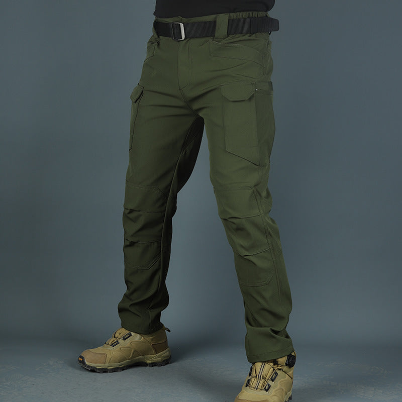 Pantaloni tattici verdi da uomo con tasche multiple, cintura nera e scarpe da trekking beige. Abbigliamento outdoor resistente e funzionale.