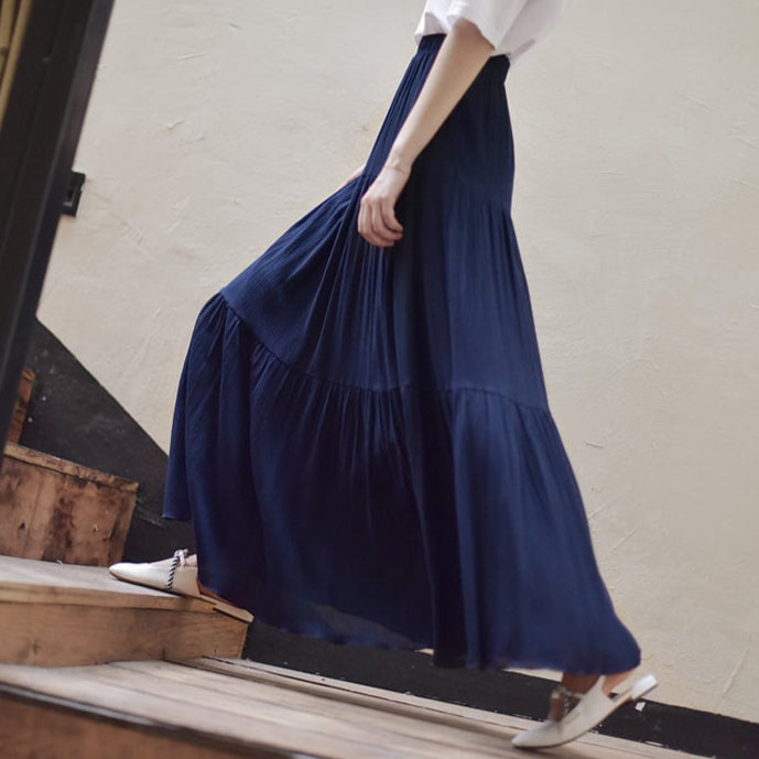 Donna con gonna lunga blu scuro, cammina su scale in legno. Moda femminile elegante, abbigliamento casual chic, tendenze abbigliamento 2023.