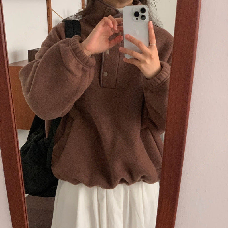 Donna con maglione marrone oversize e gonna bianca scatta selfie allo specchio con iPhone. Moda autunnale casual, stile confortevole.