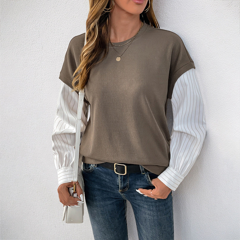 Donna con maglia a maniche lunghe marrone e bianche, jeans blu, borsa bianca, collana dorata. Moda casual autunnale, stile urbano chic.