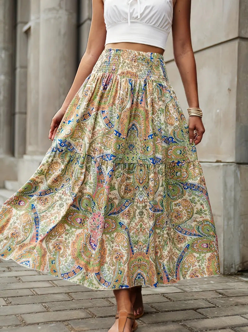 Donna con gonna lunga a fantasia paisley colorata, top bianco senza maniche, sandali, sfondo urbano. Moda estiva, abbigliamento casual elegante.