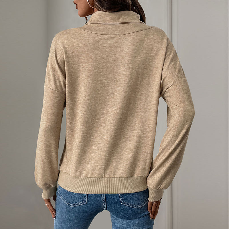 Donna di spalle indossa maglione beige a collo alto, maniche lunghe, abbinato a jeans blu. Moda casual autunnale, abbigliamento femminile elegante.