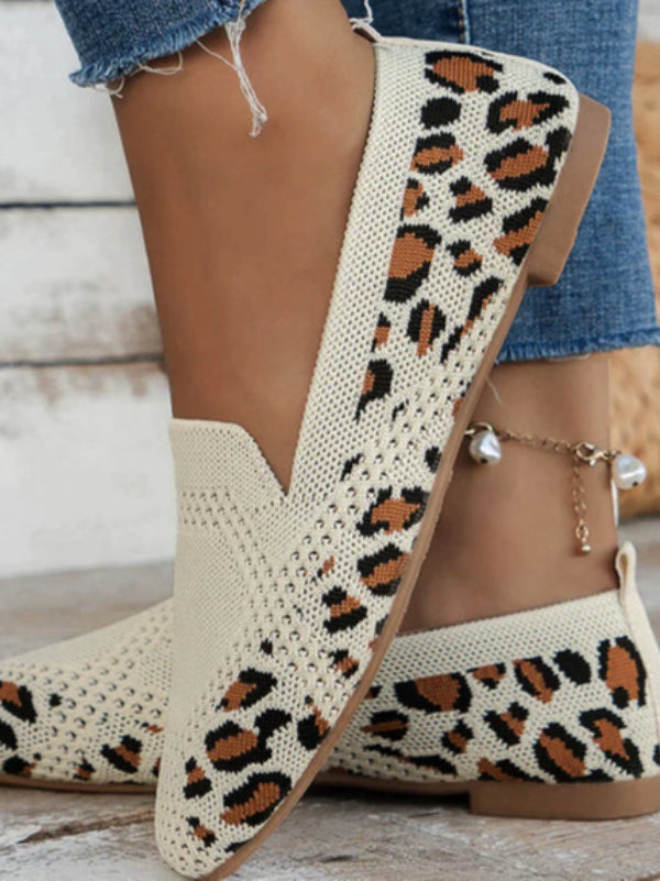 Scarpe slip-on beige con motivo leopardato, indossate con jeans. Design casual ed elegante, perfette per moda donna e tendenze calzature 2023.