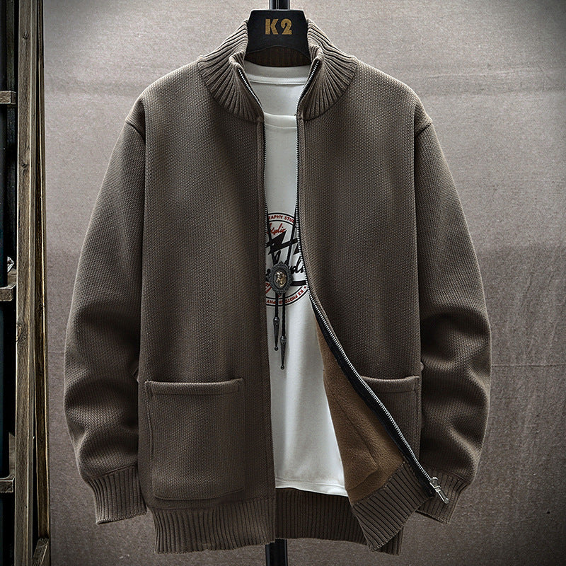 Giacca cardigan marrone con zip aperta, tasche frontali, su sfondo neutro. Indossata sopra una maglietta bianca con stampa grafica. Moda uomo casual.