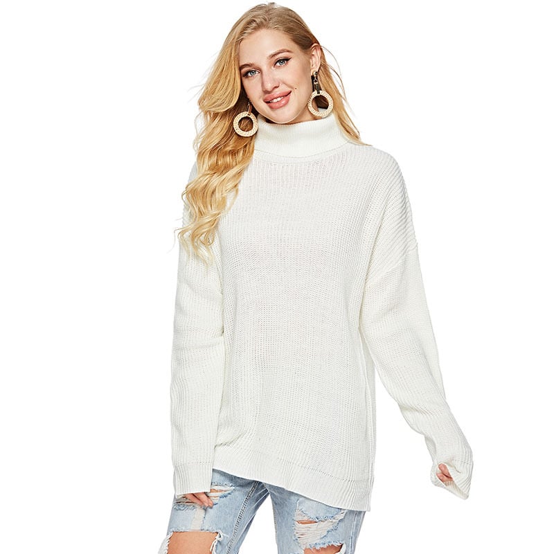Donna con maglione bianco a collo alto, jeans strappati, orecchini grandi. Moda autunnale, abbigliamento casual elegante, tendenze femminili.