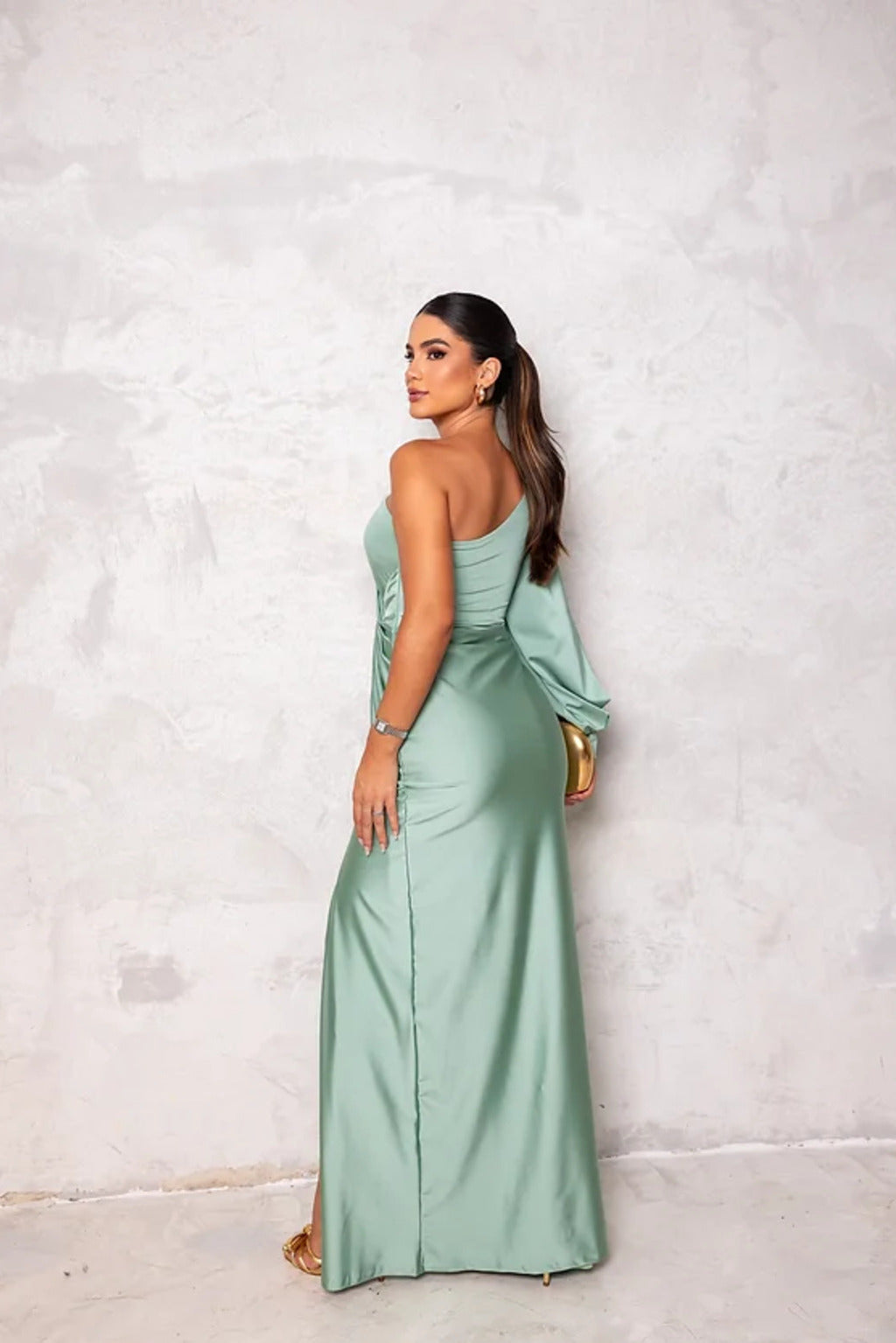 Donna in abito lungo verde menta elegante, posa di profilo su sfondo grigio. Moda femminile, abbigliamento da sera, stile sofisticato.