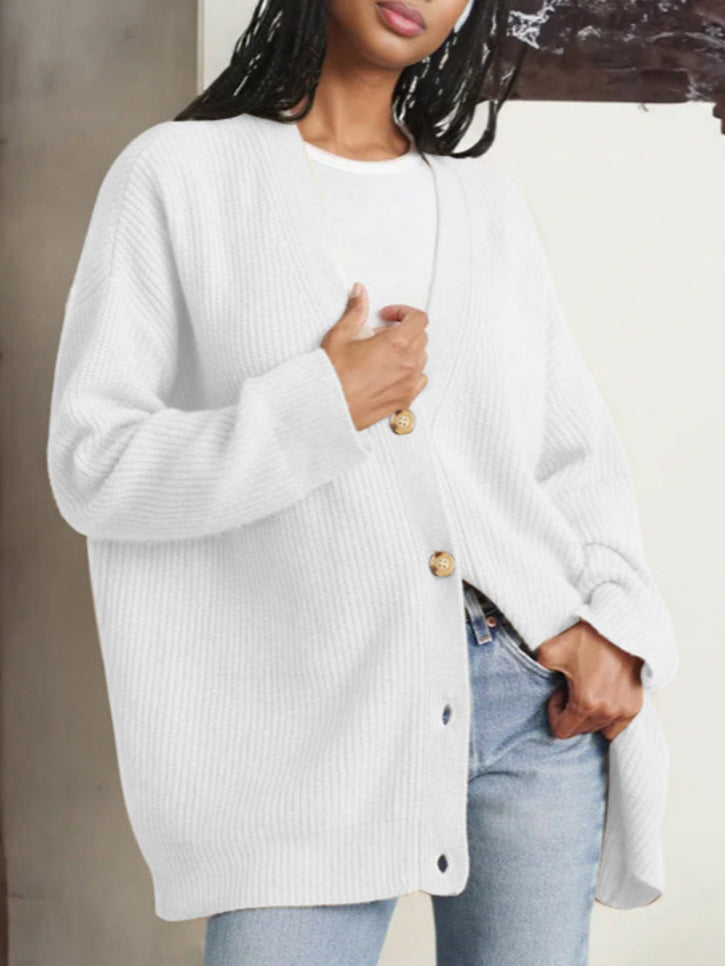 Donna indossa cardigan bianco oversize con bottoni in legno, abbinato a jeans chiari. Moda casual autunnale, stile confortevole ed elegante.
