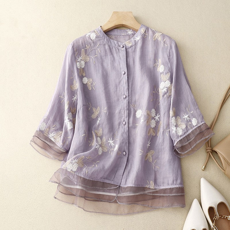 Camicia donna in lino viola con ricami floreali bianchi, maniche a tre quarti, bottoni frontali, stile elegante e casual.