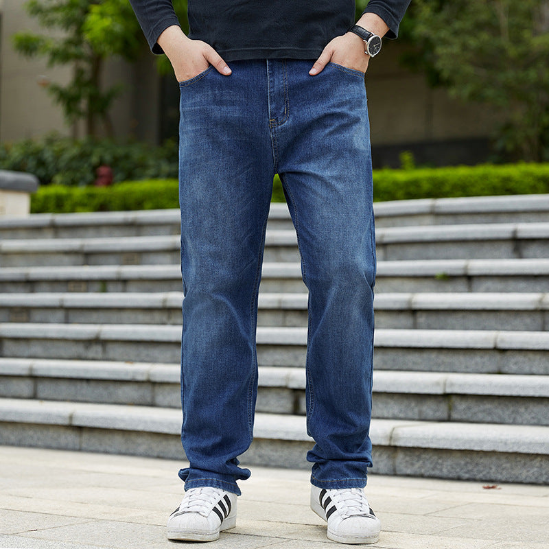 Uomo in jeans blu e scarpe da ginnastica bianche su gradini all'aperto. Moda casual maschile, abbigliamento urbano, stile quotidiano.