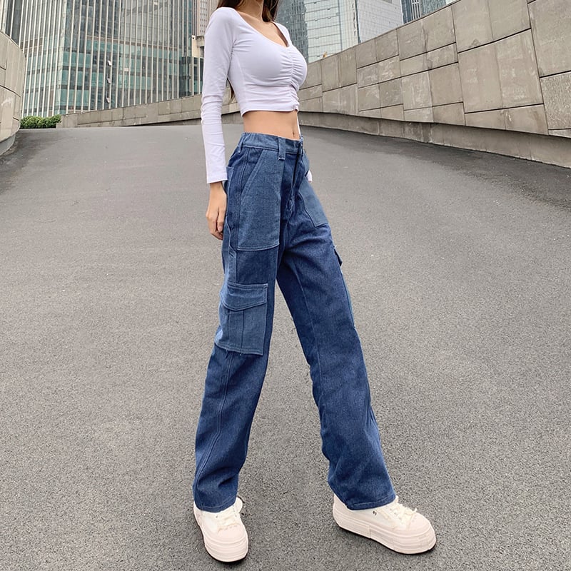 Donna con top bianco a maniche lunghe e jeans cargo blu, scarpe da ginnastica bianche, su strada urbana. Moda casual, stile urbano, abbigliamento femminile.