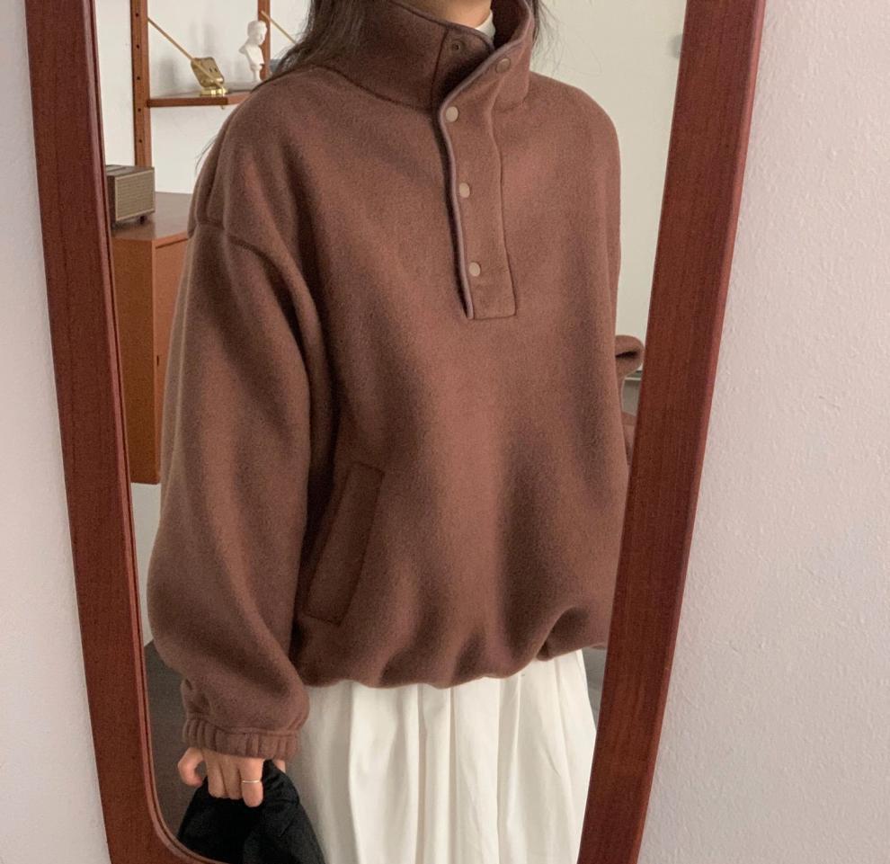 Donna con maglione marrone oversize e gonna bianca riflessa in uno specchio. Moda autunnale, abbigliamento casual elegante.