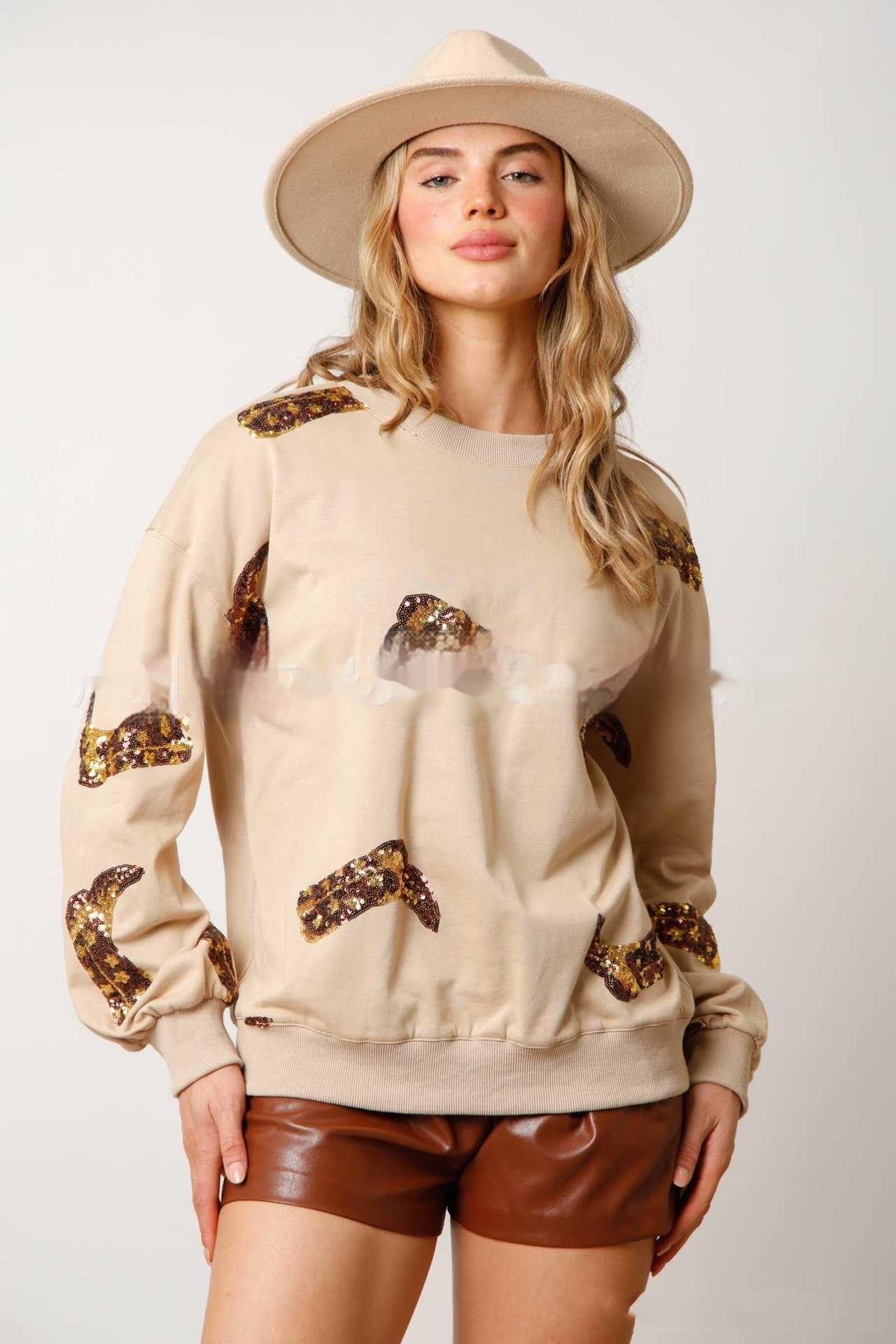Donna con cappello beige, maglione con paillettes marroni e pantaloncini in pelle marrone. Moda autunnale, abbigliamento casual chic.