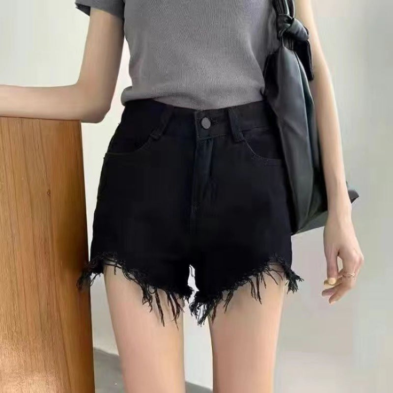 Donna con maglietta grigia e shorts neri sfrangiati, borsa a tracolla nera. Moda estiva casual, abbigliamento trendy per giovani donne.