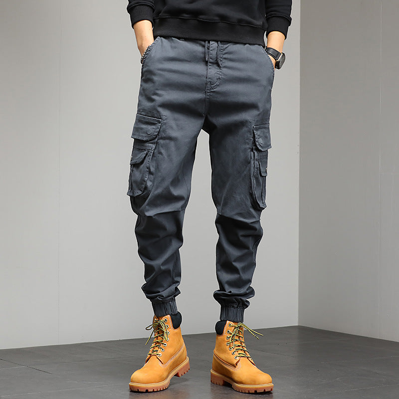 Pantaloni cargo grigi da uomo con tasche multiple, abbinati a stivali gialli in pelle. Look casual e moderno, perfetto per l'abbigliamento urbano.