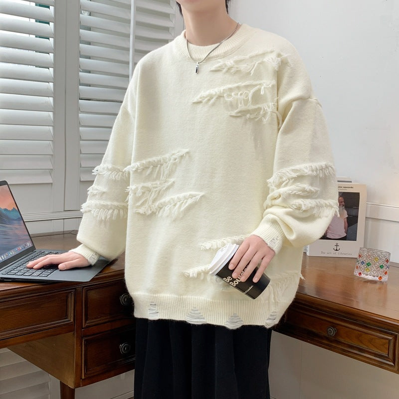 Maglione bianco oversize con dettagli sfrangiati, indossato da una persona accanto a un laptop su una scrivania in legno. Stile casual e moderno.