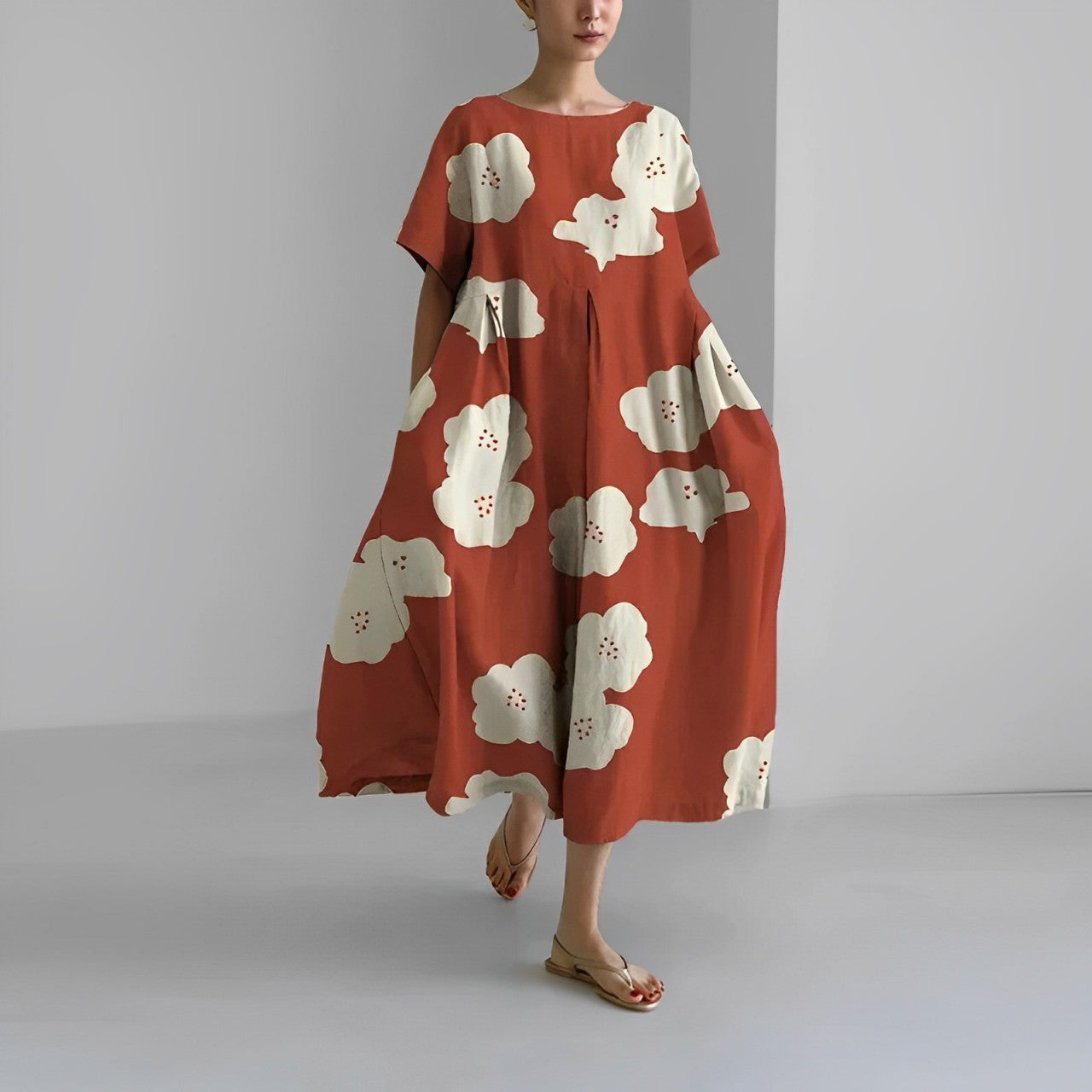 Donna con abito lungo rosso a fiori bianchi, sandali beige. Moda estiva, abbigliamento casual elegante, tendenza abiti floreali.