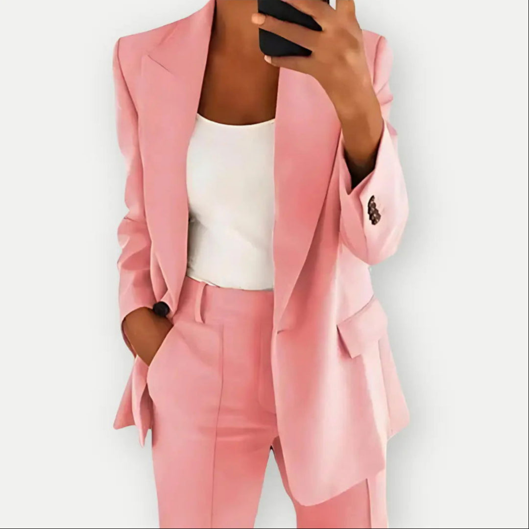 Donna in abito elegante rosa, giacca e pantaloni coordinati, con top bianco. Moda femminile, stile business casual, tendenze abbigliamento 2023.