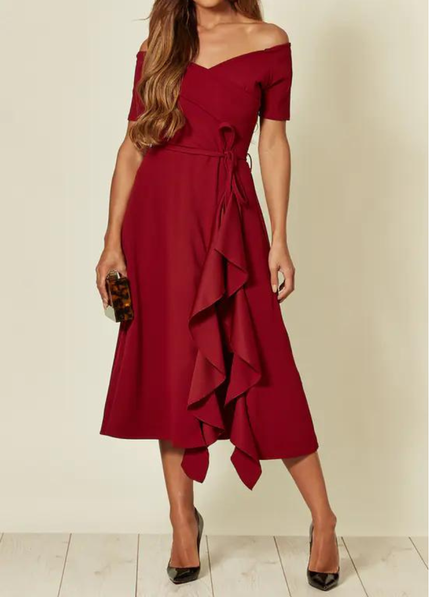 Donna in abito rosso elegante con spalle scoperte e volant, tiene una pochette marrone. Moda femminile, abbigliamento da sera, stile sofisticato.