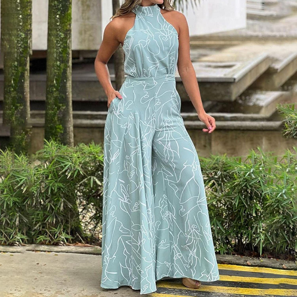 Donna con tuta elegante verde acqua, motivo linee astratte bianche, sfondo urbano con piante. Moda femminile, abbigliamento estivo chic.