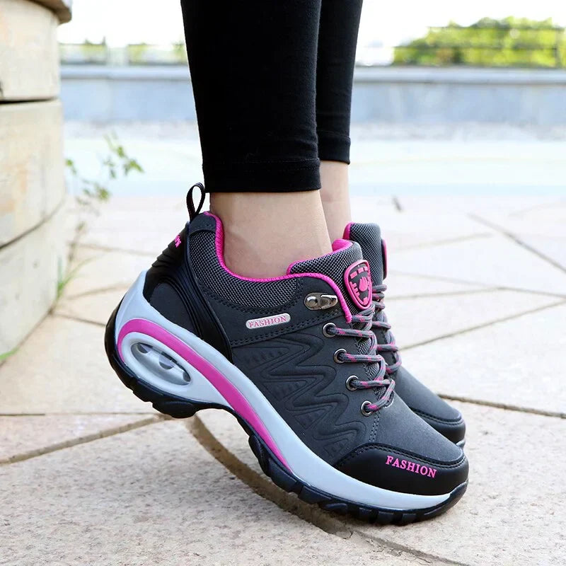Scarpe da ginnastica donna grigie e rosa con suola spessa, design moderno, indossate su pavimento esterno. Scarpe sportive moda, comfort e stile.
