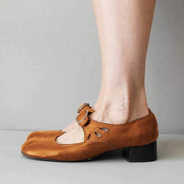 Scarpe marroni in pelle con tacco basso e cinturino, design unico con punta quadrata, indossate su piede femminile, moda calzature eleganti.