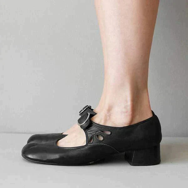 Scarpe da ballo nere con tacco basso e cinturino, indossate su pavimento grigio. Design elegante e confortevole, ideali per danza classica e moderna.