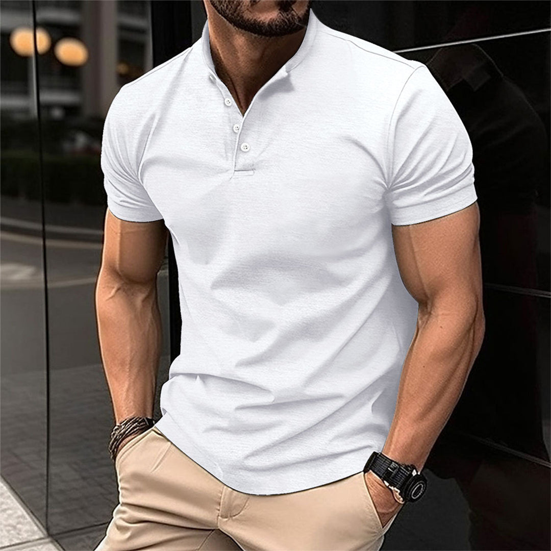 Uomo in polo bianca e pantaloni beige, in posa urbana. Moda maschile casual, stile estivo, abbigliamento elegante. Sfondo cittadino moderno.