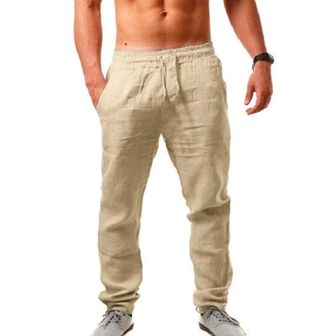 Pantaloni uomo in lino beige, stile casual, con tasche laterali. Ideali per look estivo, abbinati a scarpe sportive grigie.