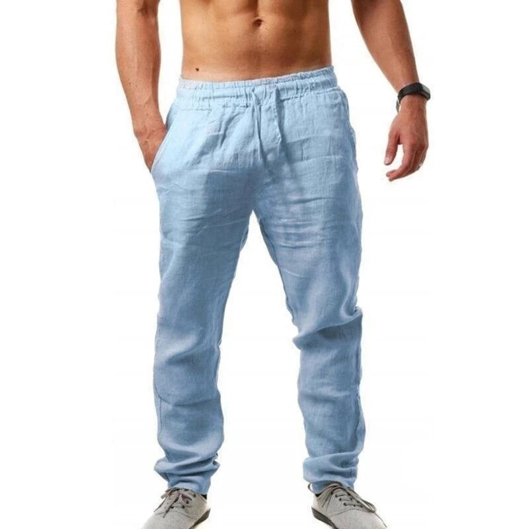 Uomo in pantaloni di lino azzurri, casual e leggeri, con scarpe sportive grigie. Moda estiva maschile, abbigliamento comodo e traspirante.