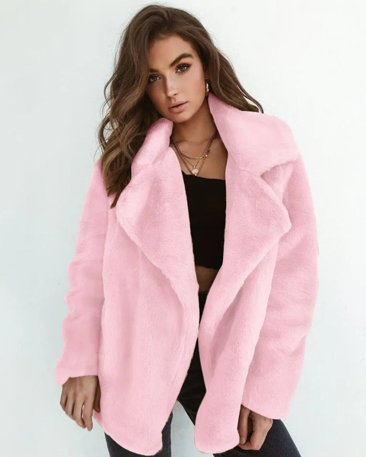 Donna con cappotto rosa in pelliccia sintetica, top nero e collana dorata. Moda autunnale, abbigliamento elegante, tendenze 2023.