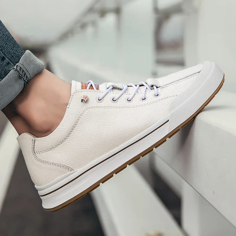 Scarpe da ginnastica bianche eleganti, suola in gomma marrone, lacci bianchi, indossate con jeans. Scarpe casual uomo, moda urbana.