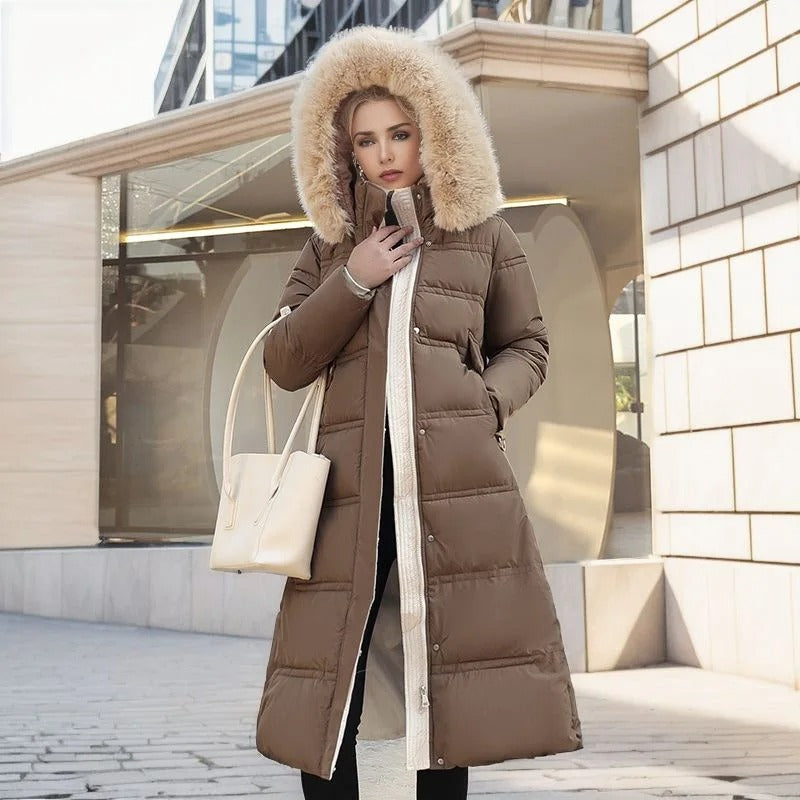Donna con cappotto lungo marrone con cappuccio in pelliccia, borsa bianca, sfondo urbano moderno. Moda invernale, abbigliamento caldo, stile elegante.