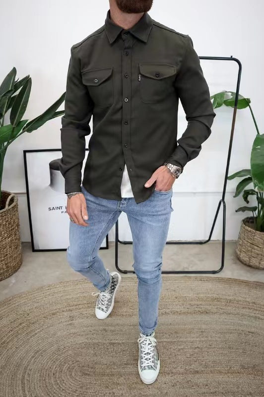 Uomo in camicia verde militare e jeans chiari, posa moderna. Scarpe da ginnastica bianche, piante decorative e poster sullo sfondo. Moda casual uomo.