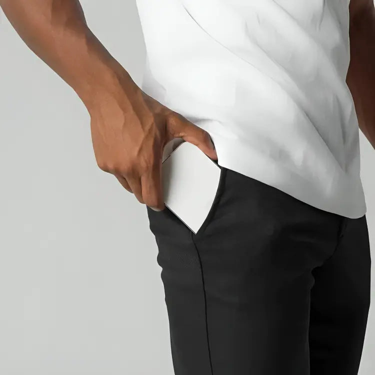 Uomo in pantaloni neri mette smartphone bianco in tasca. Tecnologia mobile, design moderno, accessori eleganti, praticità quotidiana.