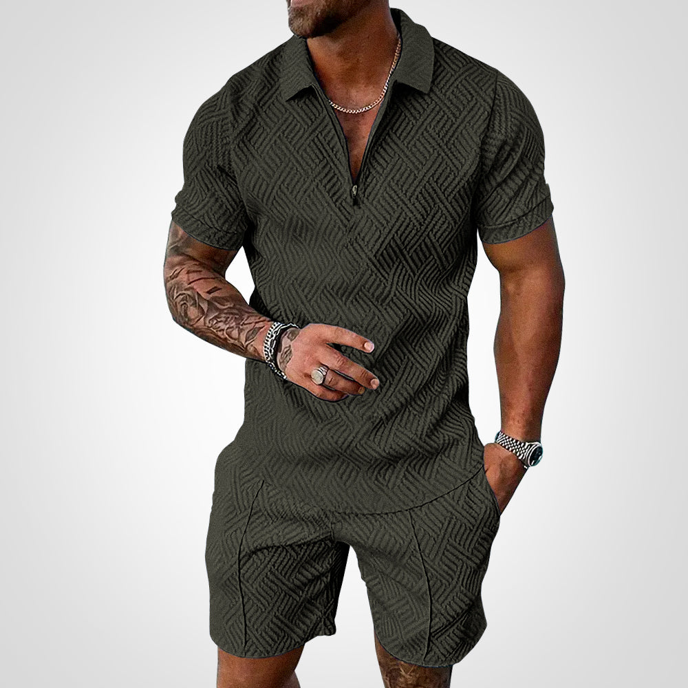 Uomo con completo estivo verde scuro, motivo geometrico, maniche corte, collana e orologio. Moda maschile casual elegante.