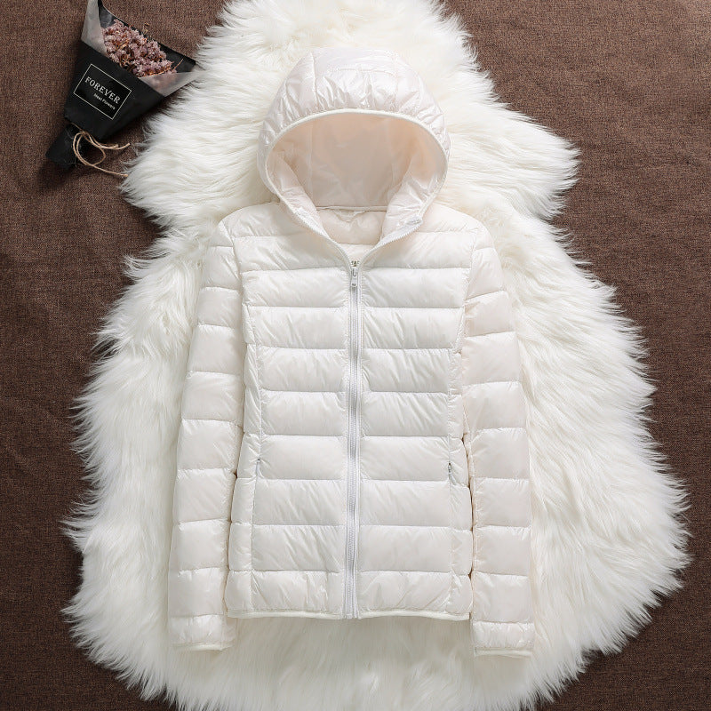 Giacca piumino bianca con cappuccio su tappeto di pelliccia bianca, elegante e calda, ideale per l'inverno. Design moderno e versatile.
