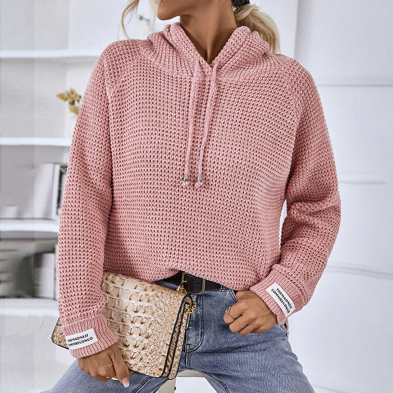 Donna con maglione rosa a maglia grossa, jeans blu e borsa beige intrecciata. Moda casual autunnale, abbigliamento femminile trendy.