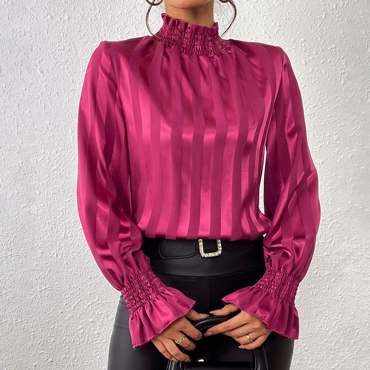 Blusa elegante in raso rosa con colletto alto e maniche a sbuffo, abbinata a pantaloni in pelle nera. Moda femminile, abbigliamento chic.