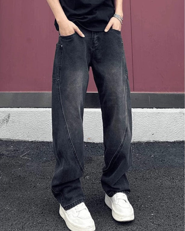 Jeans larghi neri da uomo, stile casual, con scarpe da ginnastica bianche, sfondo rosso e pavimento scuro. Moda streetwear maschile.